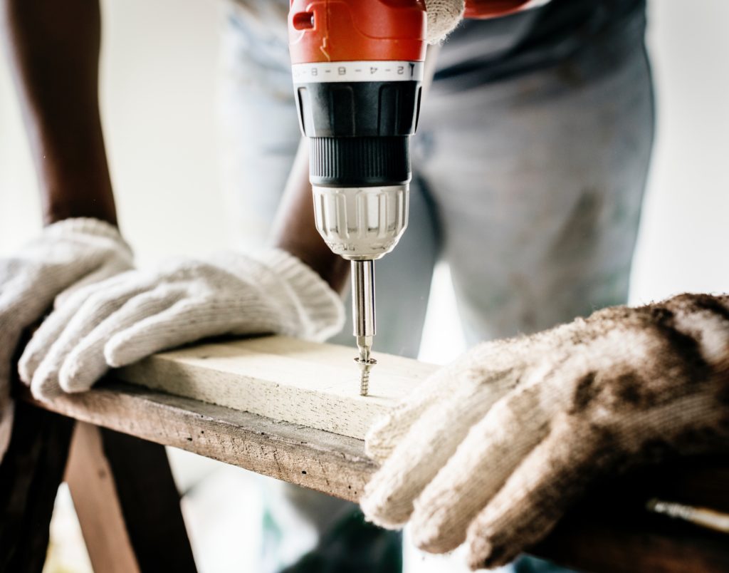 A carpenter screwing a nail into wood