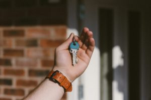 A hand holding keys in front of a front door