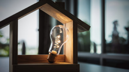 Light bulb with wood house on the table, a symbol for construction, Creative light bulb idea, power energy or business idea concept ecology, loan, mortgage, property or home.