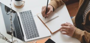 man taking notes near laptop