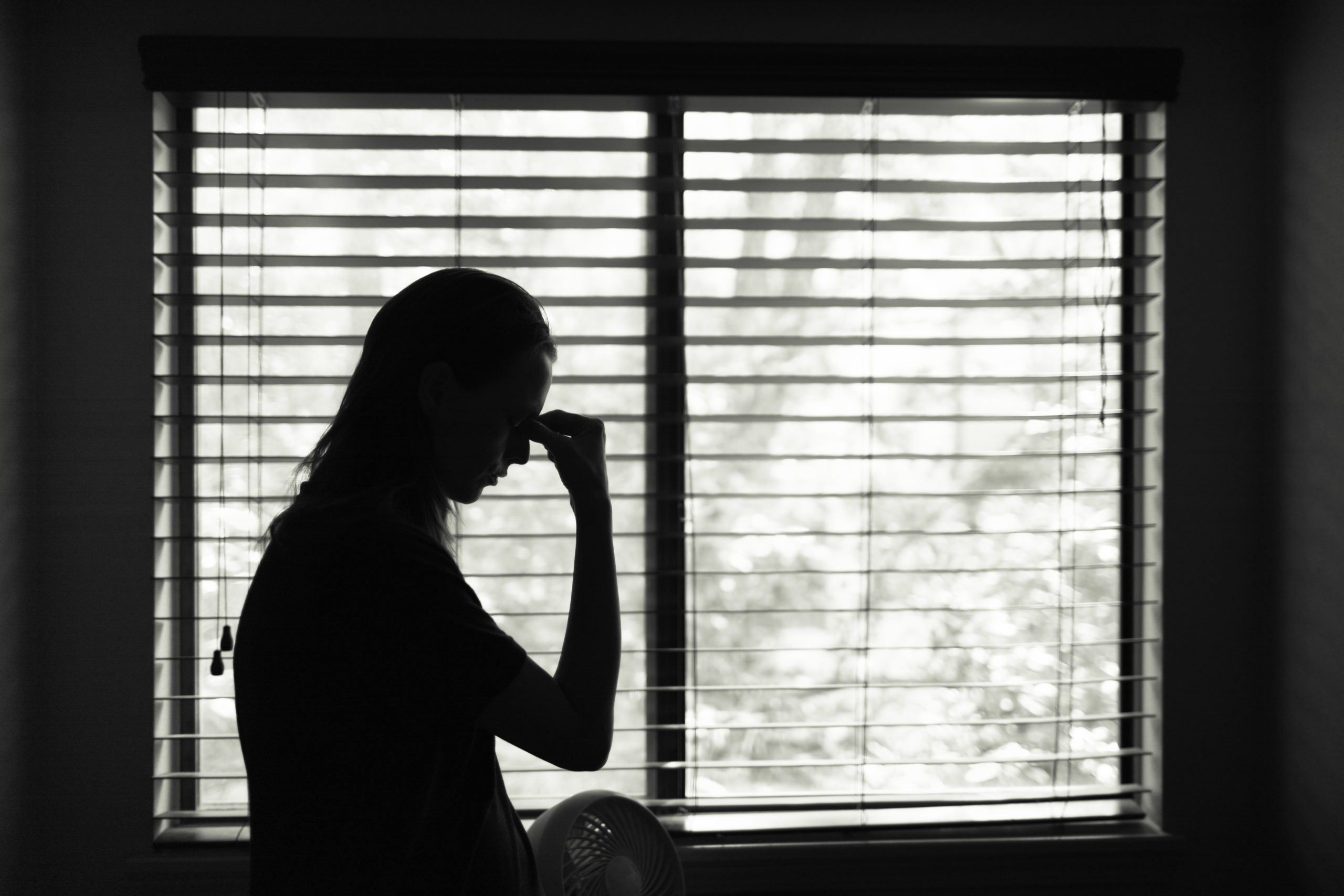 Stressed woman standing next to window